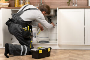 Plumber fixing sink under cabinet -Best Plumbing Services in Vail, AZ | Red Coyote Plumbing LLC